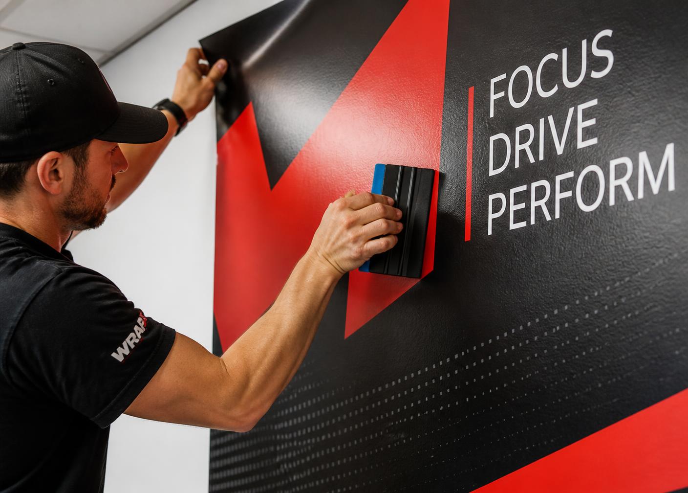 Installer squeegeeing a printed vinyl wall graphic onto an interior office wall